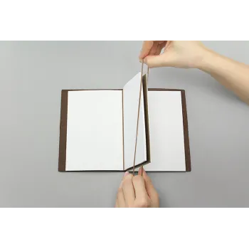 hand connecting two passport refills with traveler’s company rubber bands